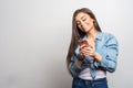 Portrait of a young happy smiling girl holding her pink smartphone and reading or watching something on it