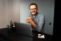 Portrait of young happy smiling man working home at laptop, looking at the camera, wearing eyeglasses and shirt. Royalty Free Stock Photo