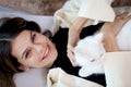 Portrait of young happy smiling woman comfortably lying on sofa in living room with cute white Persian cat sitting on her, girl Royalty Free Stock Photo