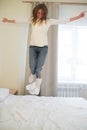 Portrait of a young happy woman jumping on the bed Royalty Free Stock Photo