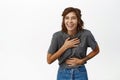 Portrait of young happy woman laughing and smiling, genuine emotions, watching smth funny, chuckle, standing in grey