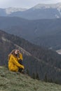 Portrait of young happy woman in mountains enjoying clean air and nature. Girl sits on side of mountain. Vertical view Royalty Free Stock Photo