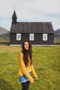 Portrait of young happy woman near Famous black church of Budir in Iceland.