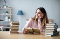 Portrait of young happy woman sits at a table with books studying at home Royalty Free Stock Photo