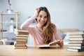 Portrait of young happy woman sits at a table with books studying at home Royalty Free Stock Photo