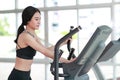 Portrait of young healthy and sporty woman using exercise machine in gym Royalty Free Stock Photo