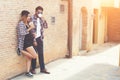 Portrait of young hipster couple posing with her boyfriend holding a cup of coffee enjoying holiday together against brick wall b Royalty Free Stock Photo