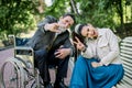 Portrait of young hipster modern girl with dreadlocks, sitting on bench, with the senior handicapped man in wheelchair Royalty Free Stock Photo