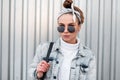 Portrait of young hipster woman in fashionable sunglasses with a stylish hairstyle in a knitted white vintage sweater in a denim Royalty Free Stock Photo