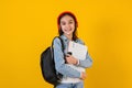 Portrait of young hispanic child teen girl student with headphones listening music on a yellow background in Mexico Latin America Royalty Free Stock Photo