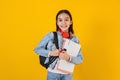 Portrait of young hispanic child teen girl student with headphones listening music on a yellow background in Mexico Latin America Royalty Free Stock Photo