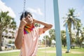 portrait of young hispanic gay boy sitting on swing with eyes closed, wearing pink polo shirt - horizontal image Royalty Free Stock Photo