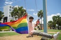 portrait of young hispanic gay boy swinging with LGBT flag, wearing pink polo shirt - horizontal image Royalty Free Stock Photo