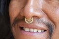 Man with long hair wearing a metal septum piercing at his nose