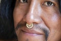 Man with long hair wearing a metal septum piercing at his nose