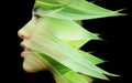 A double exposure portrait of a young woman's profile against black background with fresh green leaves Royalty Free Stock Photo