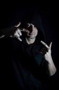 Portrait of a young hooded man making a sign of the horns with both hands in the shadow Royalty Free Stock Photo