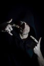 Portrait of a young hooded man making a sign of the horns with both hands in the shadow Royalty Free Stock Photo
