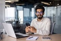 Portrait of a young Indian businessman, office worker sitting at a desk and talking on the phone, smiling and looking at Royalty Free Stock Photo