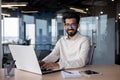 Portrait of a young Indian businessman working in the office at a laptop, smiling and looking at the camera Royalty Free Stock Photo