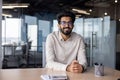 Portrait of a young Indian designer, engineer. of an architect sitting in the office at the desk and smilingly looking Royalty Free Stock Photo