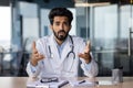 Portrait of a young Indian doctor talking seriously and worriedly to the camera. He sits in the office and communicates Royalty Free Stock Photo