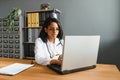 Portrait of young indian doctor working in the hospital while looking at laptop and write on clipboard. Royalty Free Stock Photo