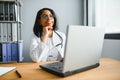 Portrait of young indian doctor working in the hospital while looking at laptop and write on clipboard. Royalty Free Stock Photo