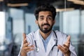 Portrait of a young Indian male doctor, psychologist who conducts online consultation with patients. Smiling, looking at Royalty Free Stock Photo