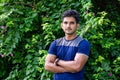 Portrait of young indian man in park on green background Royalty Free Stock Photo