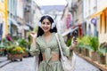 Portrait of a young Indian woman standing on the street with a phone and headphones, dancing, having fun, smiling and Royalty Free Stock Photo