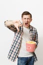 Portrait of young irritated angry handsome man in casual clothes watching movie film, holding bucket of popcorn