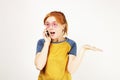 Beautiful red headed young woman posing, showing emotional facial expressions and making funny faces with mobile phone