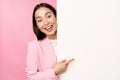 Portrait of young japanese business woman, corporate lady in suit pointing on wall with chart, showing diagram or Royalty Free Stock Photo