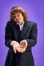 Portrait of young Jewish man with long hair and in glasses, in kippa holds hands near camera against purple background. Royalty Free Stock Photo