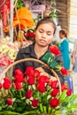 Portrait of young khmer florist women making beauty bouquet of red roses on the footpath. Phsa Thmei Market, Phnom Penh, Cambodia