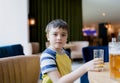 Portrait Young kid drinking fresh orange juice for breakfast in cafe, Happy child boy holding glass of fruit juice while waiting Royalty Free Stock Photo