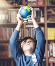 Portrait young kid holding globe high up over his head looking up from underneath with curious face, Child boy learning about Royalty Free Stock Photo