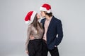 Portrait of young kissing couple in Christmas hats over white background