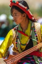 Portrait of a young Ladakhi girl wearing traditional attire and playing a traditional musical Instrument