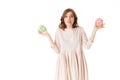 Portrait of young lady in pink dress standing with donuts in hands and thoughtfully looking in camera on white