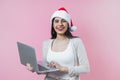 Portrait of young latin woman holding a computer with copy space in a christmas concept on pink background Royalty Free Stock Photo