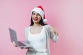 Portrait of young latin woman holding a computer with copy space in a christmas concept on pink background Royalty Free Stock Photo