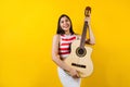 Portrait of young latin woman holding a guitar on music concept and copy space on yellow background in Latin America Royalty Free Stock Photo