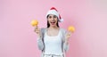 Portrait of young latin woman holding maracas rattle with copy space in a christmas concept on pink background