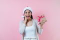 Portrait of young latin woman holding a present box with copy space in a christmas concept on pink background Royalty Free Stock Photo