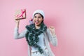 Portrait of young latin woman holding a present box with copy space in a christmas concept on pink background Royalty Free Stock Photo