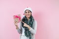 Portrait of young latin woman holding a present box with copy space in a christmas concept on pink background Royalty Free Stock Photo