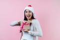 Portrait of young latin woman holding a present box with copy space in a christmas concept on pink background Royalty Free Stock Photo
