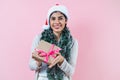 Portrait of young latin woman holding a present box with copy space in a christmas concept on pink background Royalty Free Stock Photo